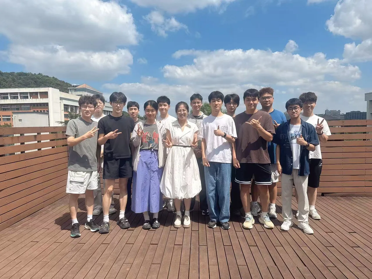 Lab members posing together outdoors with trees and campus buildings in the background